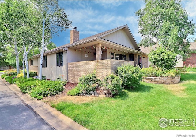 1357 43rd Ave Unit 60, Greeley, CO 80634 - view of side of home with brick siding, a chimney, and a yard