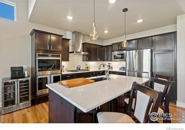 2772 Vallecito St, Timnath, CO 80547 - kitchen with appliances with stainless steel finishes, wall chimney range hood, beverage cooler, light wood-style flooring, and dark brown cabinets