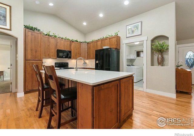 83 Evans St, Severance, CO 80550 - kitchen with black appliances, washer and dryer, light wood-style floors, light countertops, and lofted ceiling