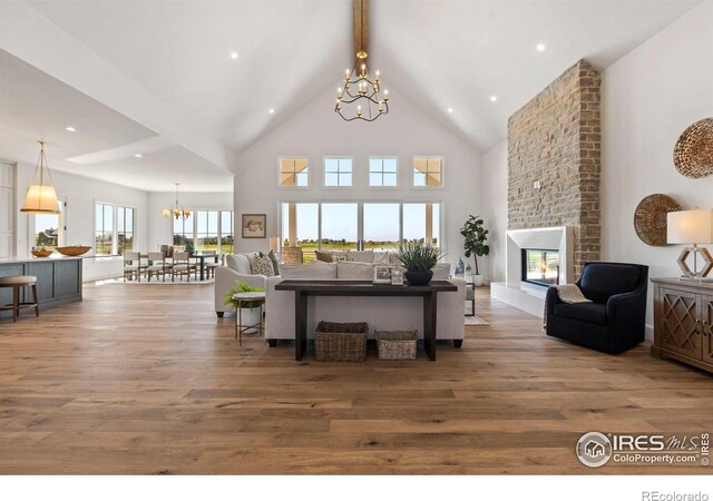 2568 Southwind Rd, Berthoud, CO 80513 - living area featuring a chandelier, high vaulted ceiling, wood finished floors, beam ceiling, and a brick fireplace