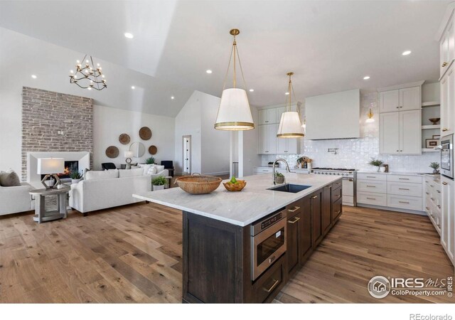 2568 Southwind Rd, Berthoud, CO 80513 - kitchen with stainless steel appliances, open floor plan, dark brown cabinetry, white cabinets, and wood finished floors