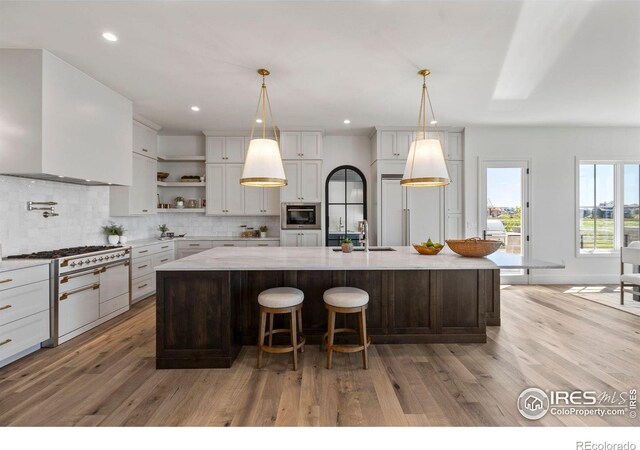 2568 Southwind Rd, Berthoud, CO 80513 - kitchen featuring open shelves, light wood-style floors, tasteful backsplash, a spacious island, and white cabinets