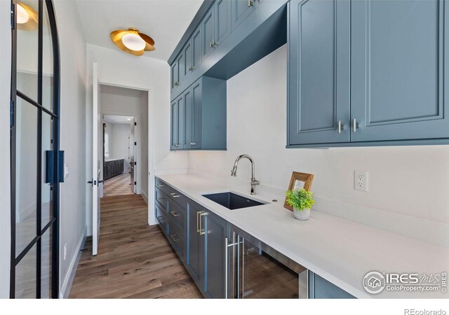 2568 Southwind Rd, Berthoud, CO 80513 - kitchen with beverage cooler, blue cabinets, wood finished floors, and light countertops