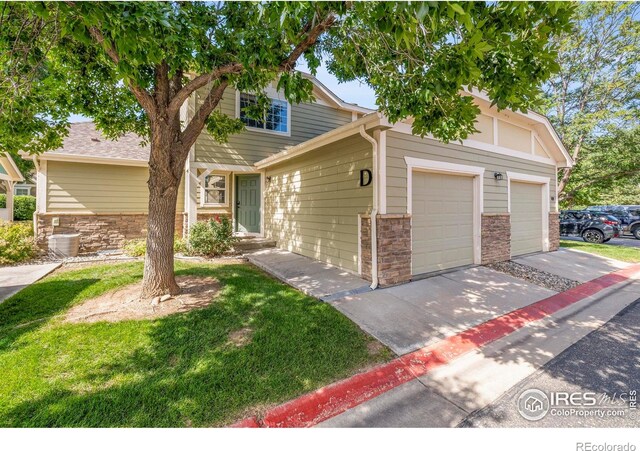 1014 Andrews Peak Dr Unit D112, Fort Collins, CO 80521 - view of front of home with concrete driveway, stone siding, an attached garage, and a front yard