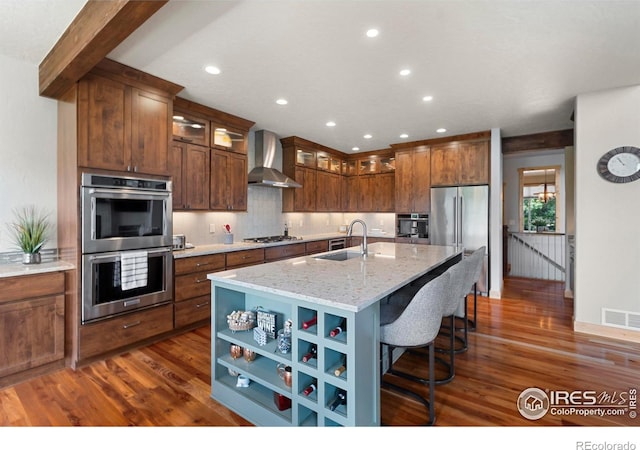 37044 Soaring Eagle Cir, Severance, CO 80550 - kitchen featuring appliances with stainless steel finishes, wall chimney range hood, dark wood-style floors, a center island with sink, and recessed lighting