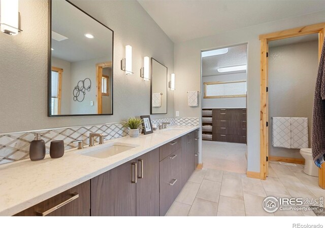37044 Soaring Eagle Cir, Severance, CO 80550 - bathroom featuring double vanity, tile patterned floors, and decorative backsplash