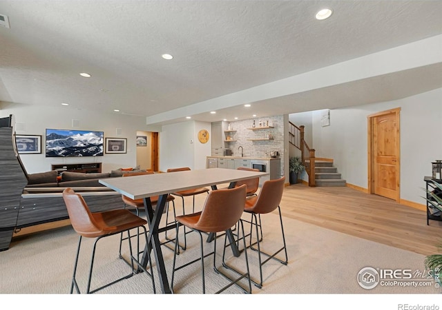 37044 Soaring Eagle Cir, Severance, CO 80550 - dining area featuring wet bar, stairs, recessed lighting, light wood-type flooring, and a textured ceiling