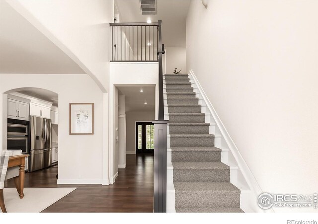 3290 Discovery Ct, Broomfield, CO 80023 - stairs featuring a towering ceiling, wood finished floors, and arched walkways