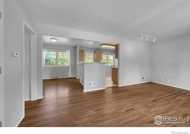 2416 15th Ave, Greeley, CO 80631 - unfurnished living room featuring wood finished floors, a textured ceiling, and plenty of natural light