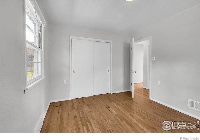 2416 15th Ave, Greeley, CO 80631 - unfurnished bedroom with wood finished floors, multiple windows, and a closet