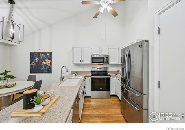 951 Vetch Cir, Lafayette, CO 80026 - kitchen with appliances with stainless steel finishes, a peninsula, light countertops, white cabinets, and light wood finished floors
