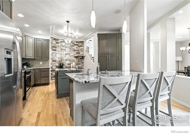 4332 Clay Commons Ct, Boulder, CO 80303 - kitchen featuring appliances with stainless steel finishes, a chandelier, backsplash, light wood-type flooring, and light stone counters