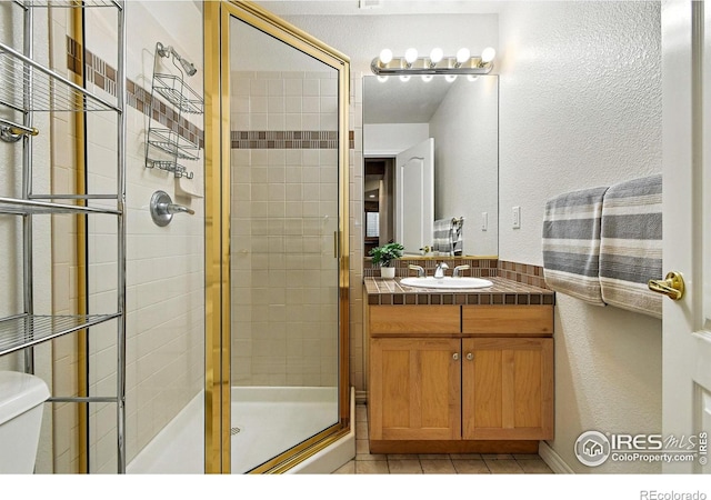 4332 Clay Commons Ct, Boulder, CO 80303 - bathroom with a shower stall, vanity, a textured wall, and tile patterned floors