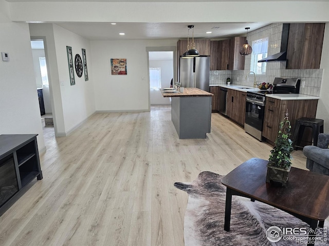 202 N 7th Ave, Sterling, CO 80751 - kitchen with appliances with stainless steel finishes, ventilation hood, tasteful backsplash, dark brown cabinetry, and light wood-type flooring