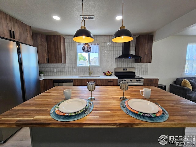 202 N 7th Ave, Sterling, CO 80751 - kitchen with stainless steel appliances, wall chimney exhaust hood, butcher block counters, tasteful backsplash, and recessed lighting