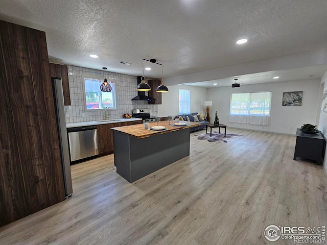 202 N 7th Ave, Sterling, CO 80751 - kitchen featuring appliances with stainless steel finishes, wood counters, a textured ceiling, light wood-type flooring, and a kitchen island