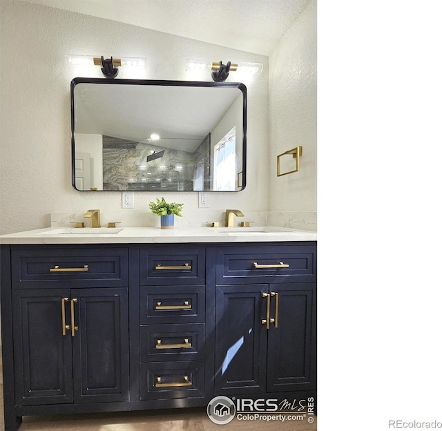 202 N 7th Ave, Sterling, CO 80751 - bathroom featuring double vanity, vaulted ceiling, a textured wall, and a shower