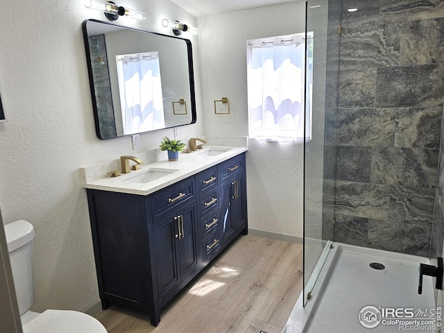 202 N 7th Ave, Sterling, CO 80751 - bathroom with wood finished floors, double vanity, tiled shower, and a textured wall