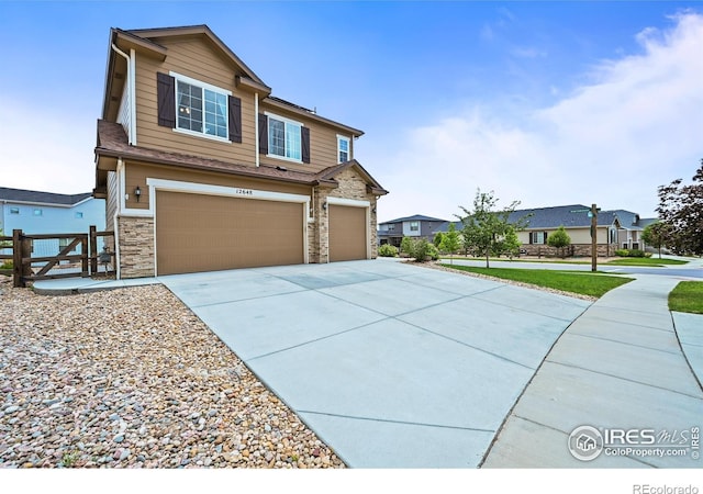 12648 Canoe St, Firestone, CO 80504 - view of front of property featuring an attached garage, concrete driveway, and stone siding