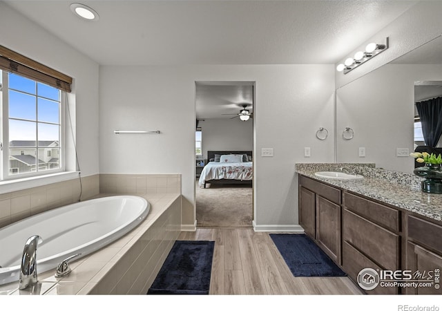 12648 Canoe St, Firestone, CO 80504 - bathroom with connected bathroom, vanity, a garden tub, wood finished floors, and ceiling fan