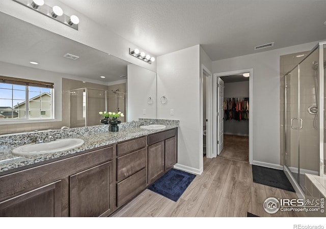 12648 Canoe St, Firestone, CO 80504 - bathroom with a stall shower, wood finished floors, double vanity, and a spacious closet