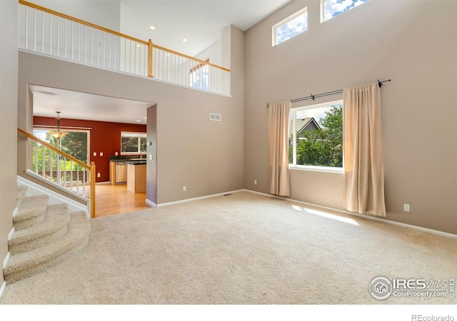 17132 E 104th Way, Commerce City, CO 80022 - unfurnished living room featuring carpet flooring, a towering ceiling, plenty of natural light, and stairway