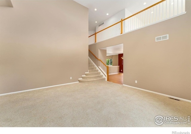 17132 E 104th Way, Commerce City, CO 80022 - unfurnished living room featuring carpet flooring, recessed lighting, a towering ceiling, and stairs