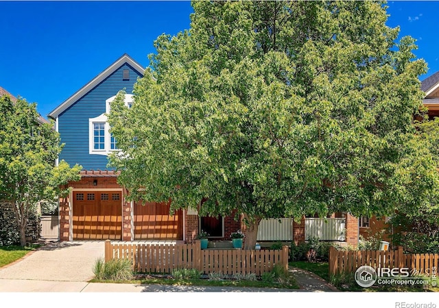 901 Terrace Cir S, Boulder, CO 80304 - obstructed view of property featuring brick siding, a fenced front yard, concrete driveway, and an attached garage