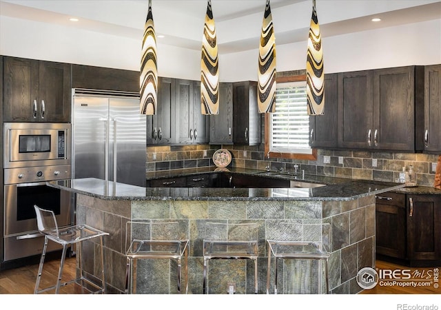 820 Pearl St, Boulder, CO 80302 - kitchen with built in appliances, dark brown cabinets, dark stone counters, tasteful backsplash, and a large island