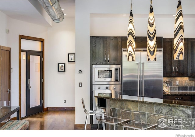 820 Pearl St, Boulder, CO 80302 - kitchen with built in appliances, dark wood-type flooring, dark brown cabinetry, decorative backsplash, and dark stone countertops