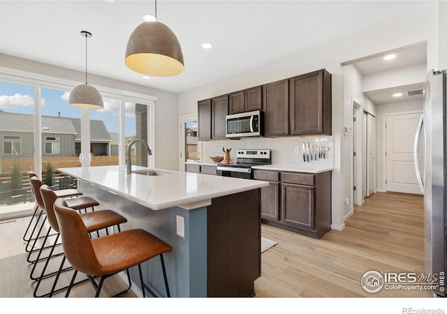 5199 Beckworth St, Timnath, CO 80547 - kitchen with appliances with stainless steel finishes, light wood-style floors, dark brown cabinets, a breakfast bar, and backsplash