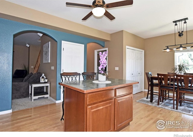 405 Ridgeview Ct, Johnstown, CO 80534 - kitchen featuring arched walkways, dark countertops, ceiling fan, and light wood-style floors