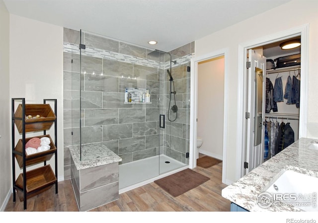 405 Ridgeview Ct, Johnstown, CO 80534 - bathroom featuring wood finished floors, a stall shower, double vanity, and a spacious closet