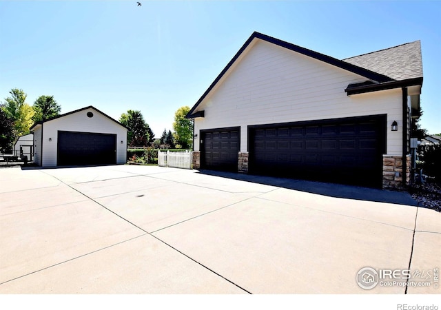 405 Ridgeview Ct, Johnstown, CO 80534 - view of home's exterior featuring stone siding, a garage, an outbuilding, and roof with shingles