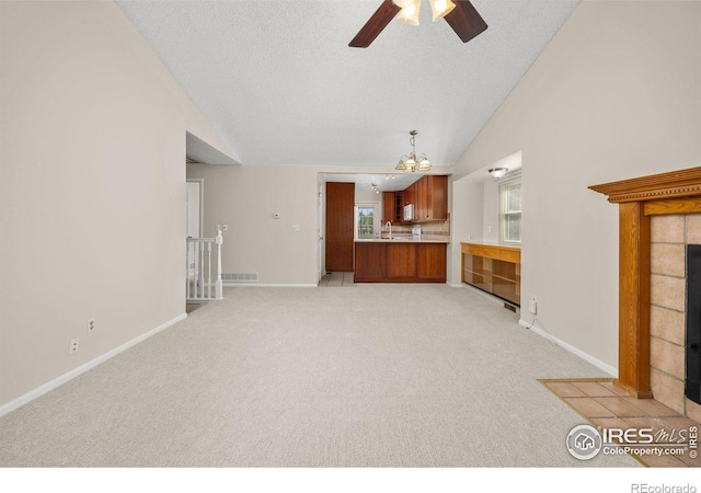 253 W Cedar Way, Louisville, CO 80027 - unfurnished living room with a tiled fireplace, a ceiling fan, light carpet, a chandelier, and a textured ceiling