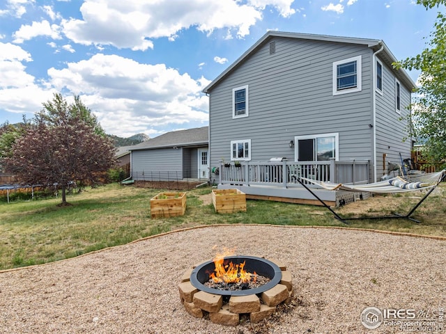 1695 Gray Hawk Ct, Estes Park, CO 80517 - back of property featuring a fire pit, a trampoline, a yard, and a wooden deck