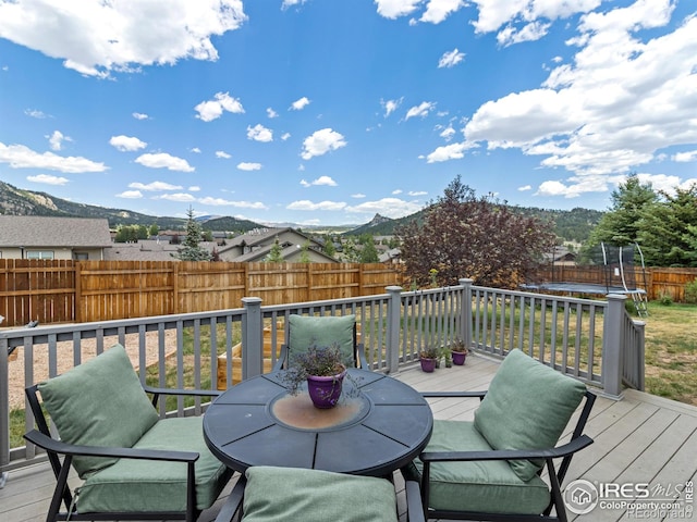 1695 Gray Hawk Ct, Estes Park, CO 80517 - wooden deck featuring a trampoline, a fenced backyard, a mountain view, and outdoor dining area