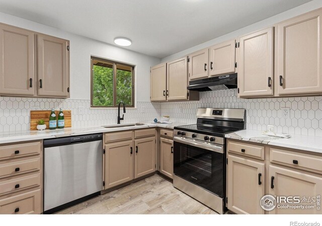 530 Mount Evans St, Longmont, CO 80504 - kitchen featuring appliances with stainless steel finishes, under cabinet range hood, light wood-style floors, light countertops, and backsplash