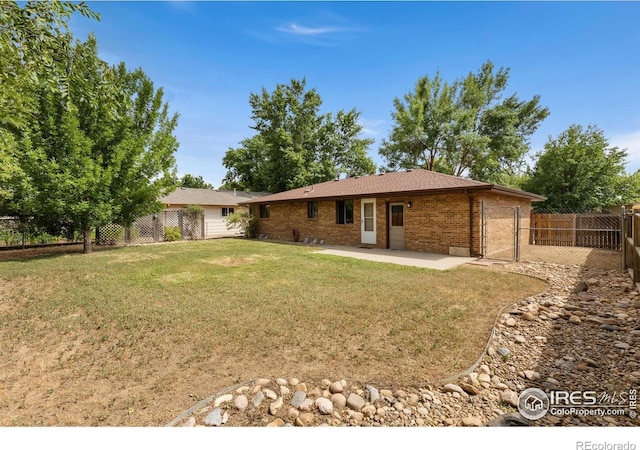 530 Mount Evans St, Longmont, CO 80504 - back of house with a patio area, brick siding, a fenced backyard, and a garage