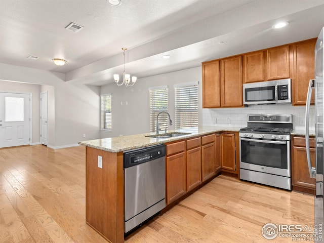 3038 County Fair Ln Unit 1, Fort Collins, CO 80528 - kitchen with appliances with stainless steel finishes, brown cabinetry, a peninsula, tasteful backsplash, and recessed lighting