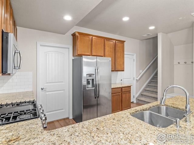 3038 County Fair Ln Unit 1, Fort Collins, CO 80528 - kitchen with appliances with stainless steel finishes, wood finished floors, light stone countertops, tasteful backsplash, and brown cabinets