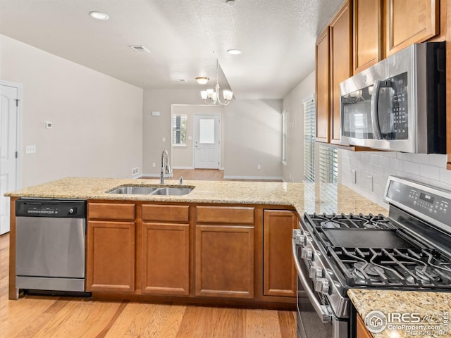 3038 County Fair Ln Unit 1, Fort Collins, CO 80528 - kitchen featuring appliances with stainless steel finishes, light wood-style flooring, a peninsula, brown cabinets, and decorative backsplash