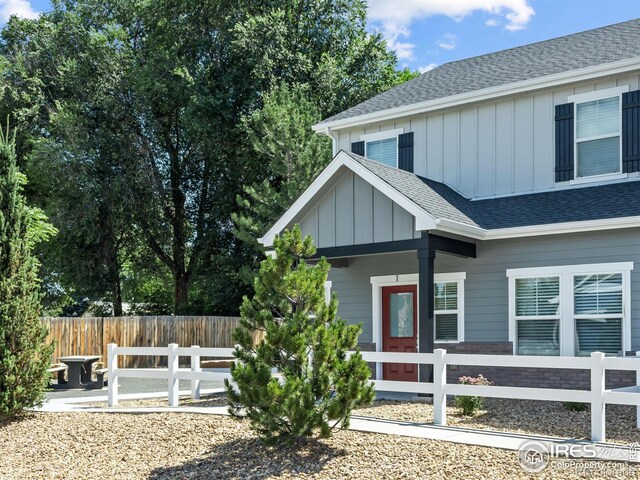 3038 County Fair Ln Unit 1, Fort Collins, CO 80528 - view of property exterior with board and batten siding, a fenced front yard, a shingled roof, and covered porch