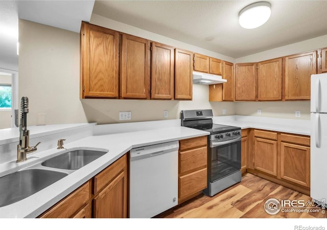 1830 W Centennial Dr Unit 108, Louisville, CO 80027 - kitchen featuring white appliances, under cabinet range hood, light wood-style flooring, light countertops, and brown cabinetry