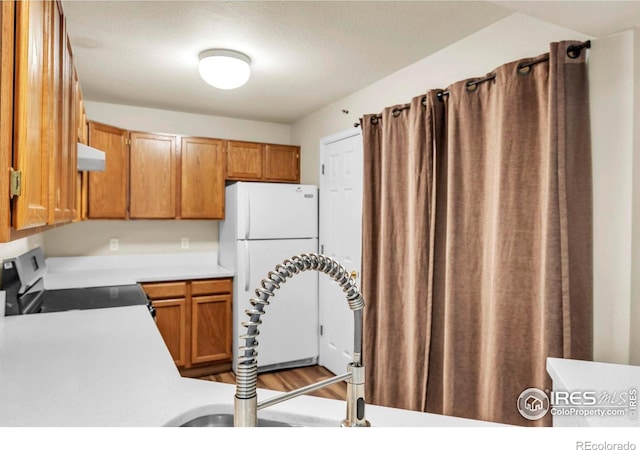 1830 W Centennial Dr Unit 108, Louisville, CO 80027 - kitchen with white appliances, light countertops, range hood, and brown cabinets