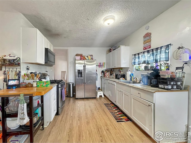 329 S Wynona Ave, Holyoke, CO 80734 - kitchen featuring appliances with stainless steel finishes, light wood-style flooring, a textured ceiling, and white cabinets