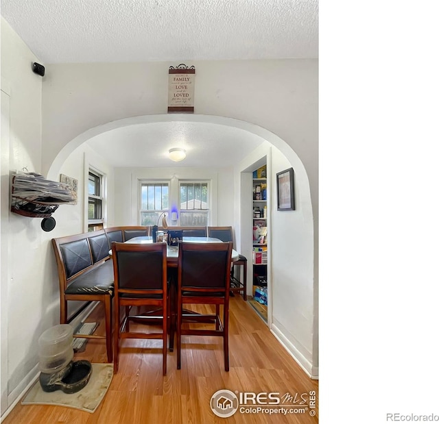 329 S Wynona Ave, Holyoke, CO 80734 - dining room featuring arched walkways, light wood finished floors, and a textured ceiling