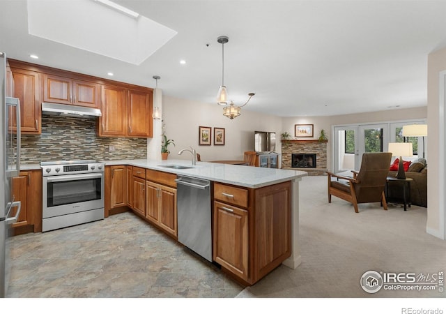 337 Arapahoe Ave Unit 303, Boulder, CO 80302 - kitchen with stainless steel appliances, a peninsula, under cabinet range hood, brown cabinetry, and tasteful backsplash
