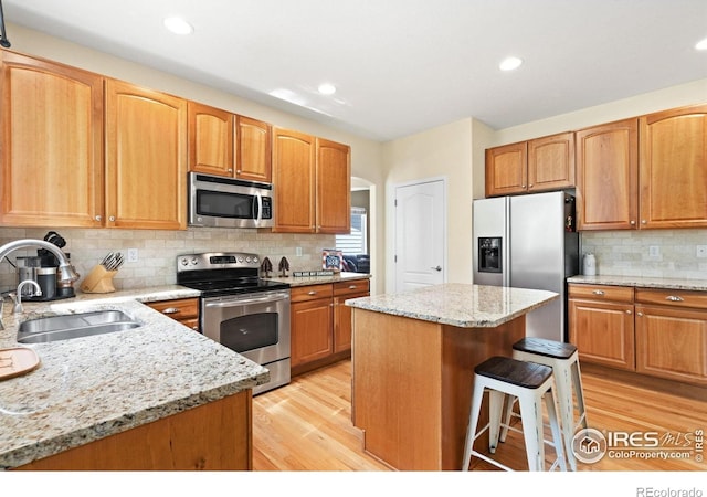 8119 Lighthouse Ln, Windsor, CO 80528 - kitchen featuring stainless steel appliances, light wood finished floors, backsplash, light stone counters, and recessed lighting