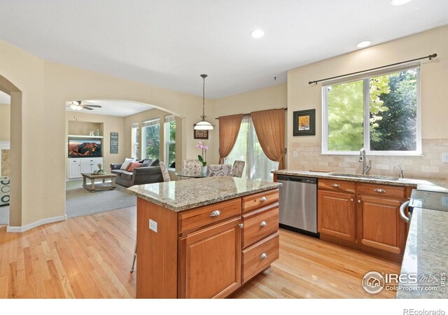 8119 Lighthouse Ln, Windsor, CO 80528 - kitchen featuring stainless steel dishwasher, arched walkways, light wood-style flooring, light stone countertops, and tasteful backsplash